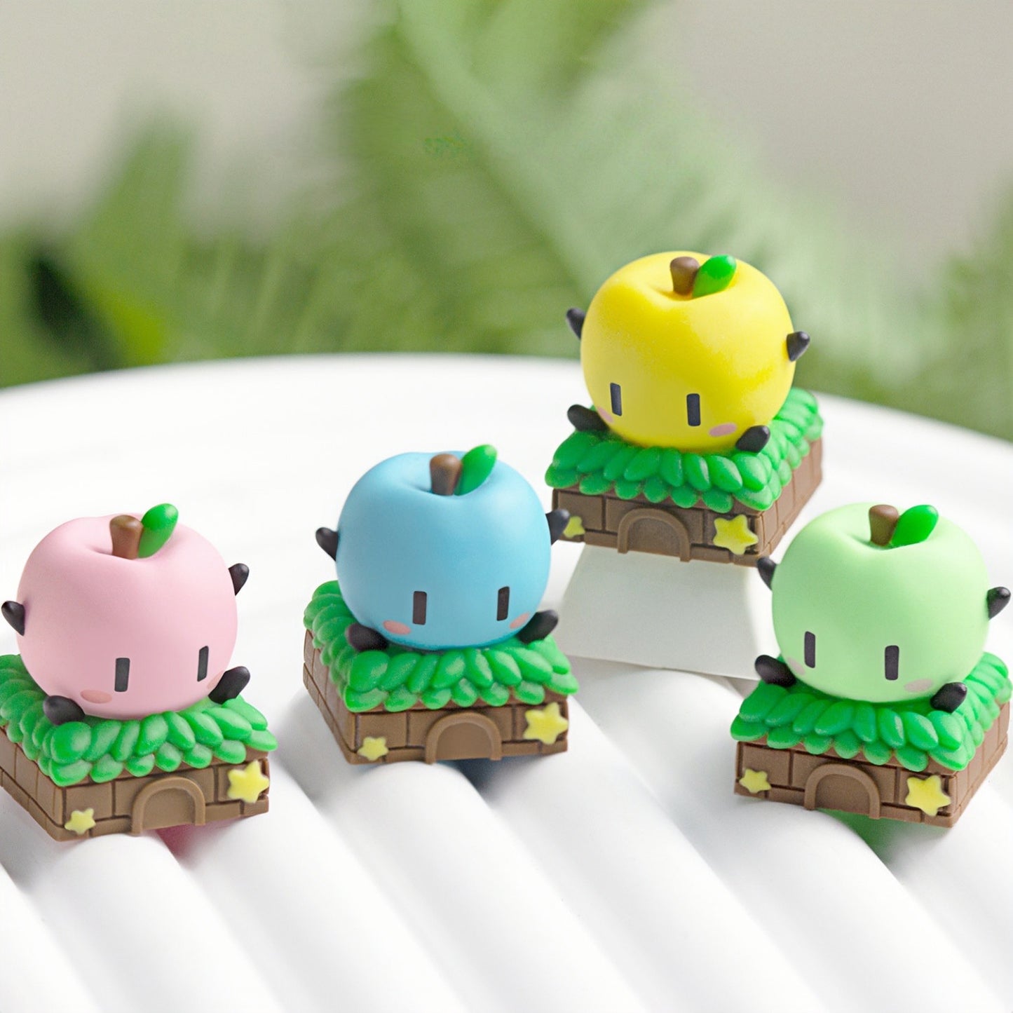 Keycapper Stardew Valley Junimo artisan keycaps collection featuring four custom colored apple sprites on a white display stand.