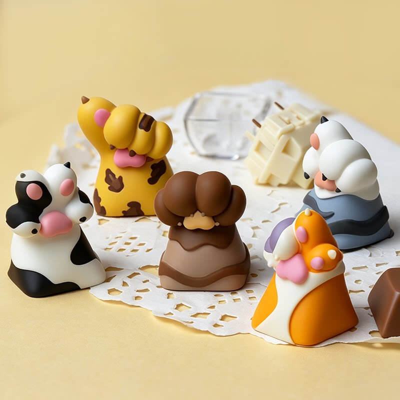 Keycapper handmade resin animal paw artisan keycaps collection featuring spotted dog paw, cat, bear, and leopard paws on a lace table runner.