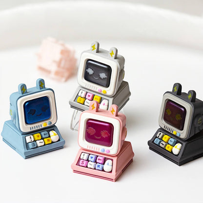 Four colorful retro computer artisan keycaps by Keycapper in blue, grey, pink, and dark grey flavors, showcasing their detailed miniature keyboards and cute monitor designs.