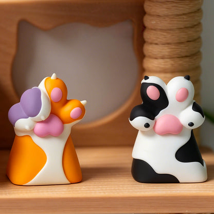Keycapper cute 3D orange calico cat paw and black white dog paw keycaps side by side in front of a cat scratcher.