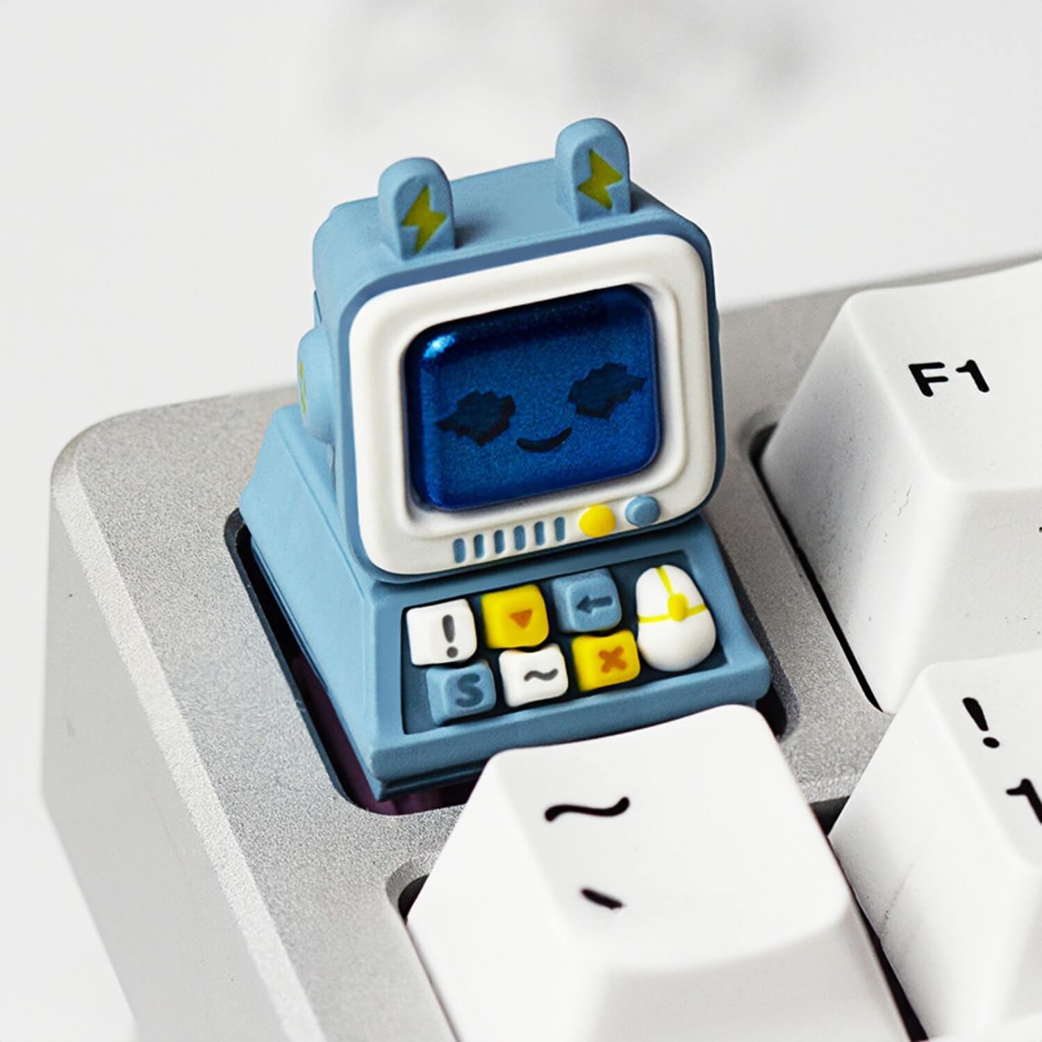 Keycapper pastel blue vintage monitor artisan keycap with a smiling pixel screen, sitting perfectly next to a white F1 keycap.