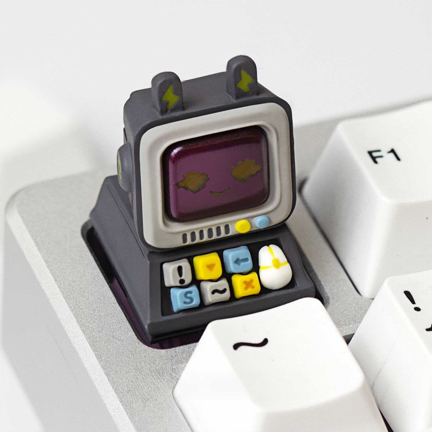 Detailed shot of a dark grey retro computer artisan keycap by Keycapper featuring a purple screen and lightning bolt ears.