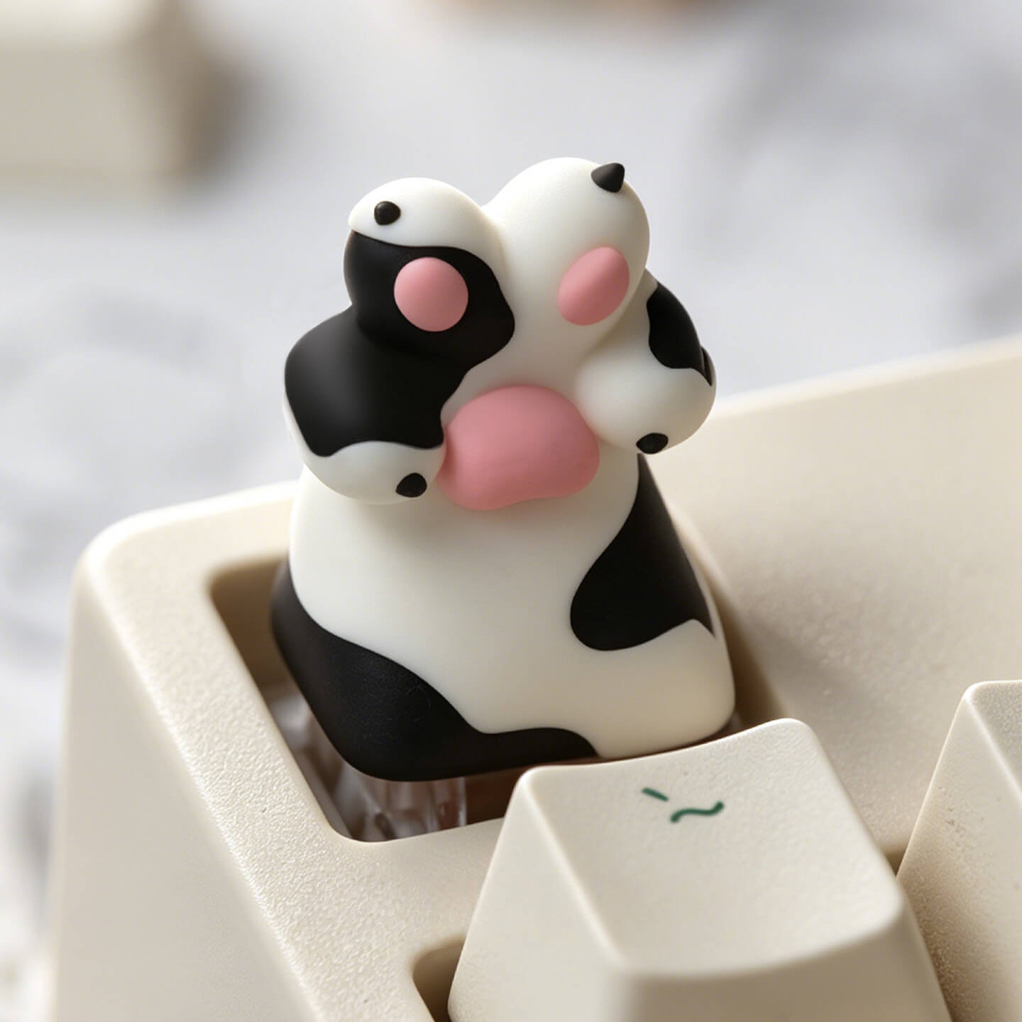 Keycapper black and white spotted dog paw resin artisan keycap with pink toe beans mounted on a mechanical keyboard.