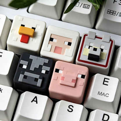 Keycapper™ Minecraft Cube Series Artisanal Keycaps – A collection shot featuring six distinct 3D voxel Animal and Monster Mob heads (Chicken, Sheep, Wolf, Cow, Pig) installed in a row on a white mechanical keyboard, showcasing the detailed pixel art.