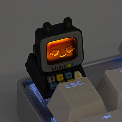Keycapper dark grey retro computer keycap illuminated in the dark, showing an amber RGB backlit glowing screen with a pixel smile.