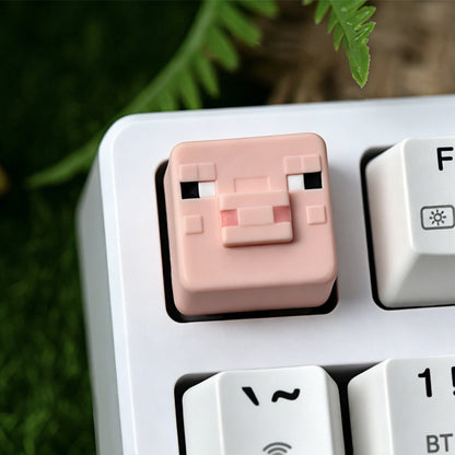 Keycapper™ Minecraft Cube Series Artisanal Keycap – A sharp focus on a pink 3D voxel Pig mob head novelty keycap, with pixelated eyes and snout, installed on the F1 key of a white mechanical keyboard.