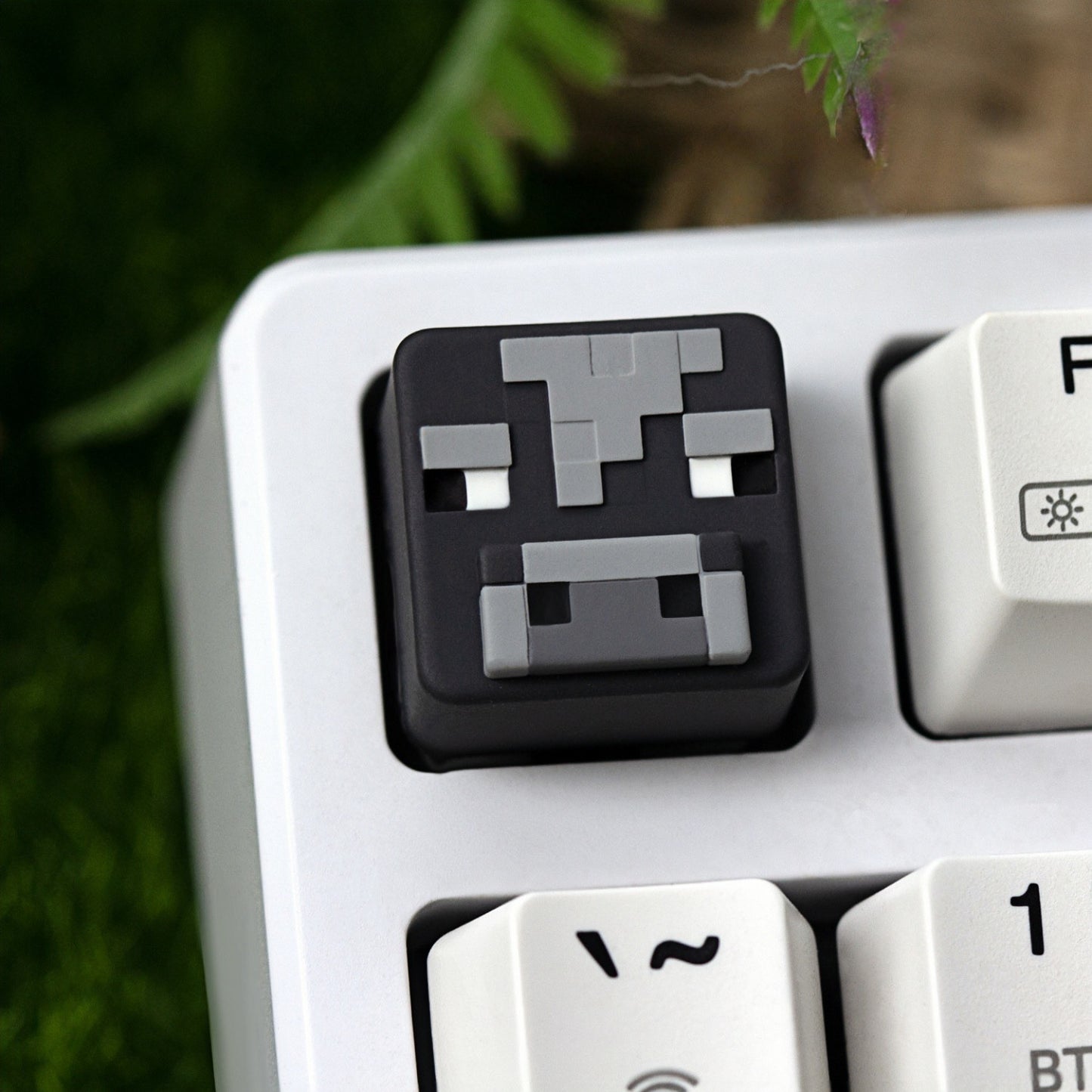 Keycapper™ Minecraft Cube Series Artisanal Keycap – A clear shot of a dark grey and light grey 3D voxel Cow mob head novelty keycap, with characteristic pixelated features, installed on the F1 key of a white mechanical keyboard.