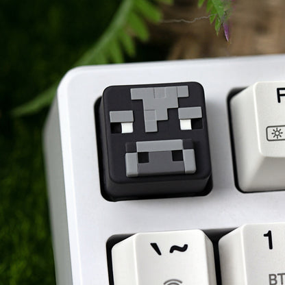 Keycapper™ Minecraft Cube Series Artisanal Keycap – A clear shot of a dark grey and light grey 3D voxel Cow mob head novelty keycap, with characteristic pixelated features, installed on the F1 key of a white mechanical keyboard.