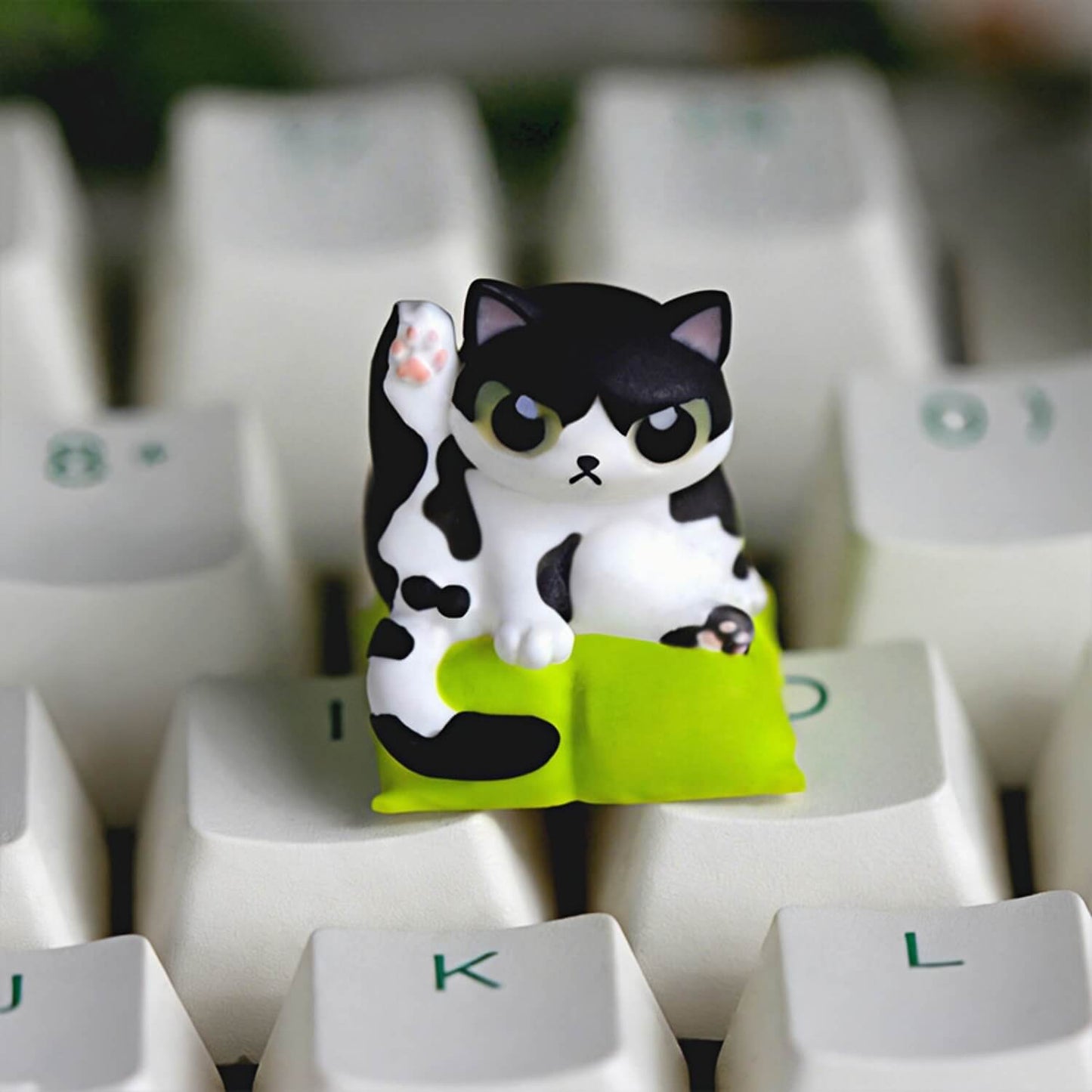 Keycapper Cat Grooming artisan keycap featuring a cute black and white Tuxedo cat lifting its leg on a lime green cushion.