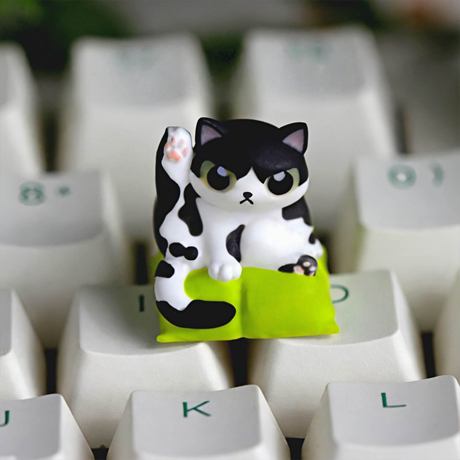 Keycapper Cat Grooming artisan keycap featuring a cute black and white Tuxedo cat lifting its leg on a lime green cushion.