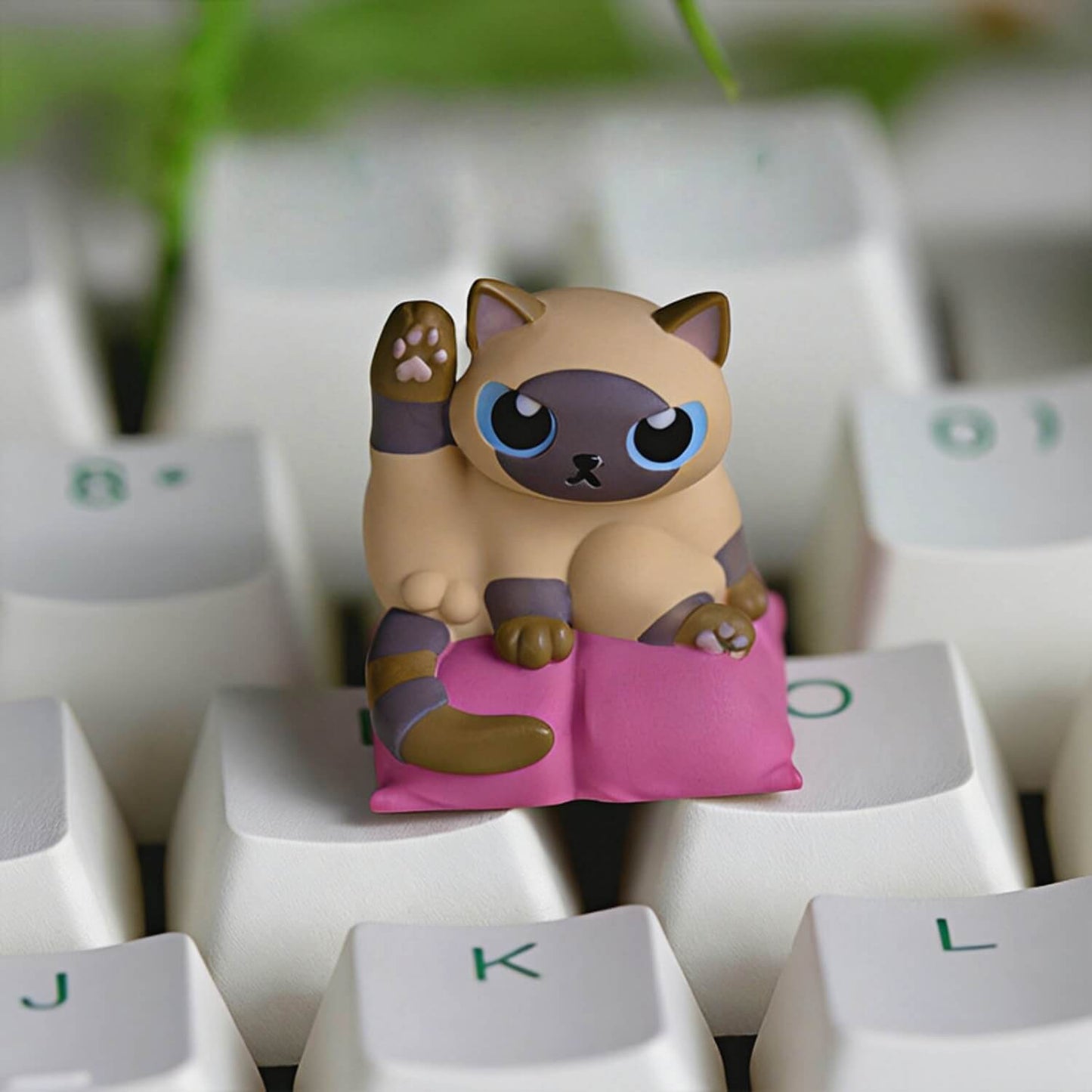 Keycapper Cat Grooming artisan keycap featuring a cute Siamese cat with blue eyes in a licking pose on a magenta cushion.